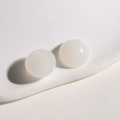 Vue macro de deux cabochons ronds en résine blanc laiteux sur un présentoir minimaliste - 1 Pièce / Blanc Gelée