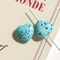 Macro shot of turquoise heart-shaped beads with black ink splatter for DIY jewelry - Blue