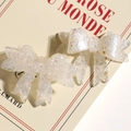 Close-up of sparkling sequined bow accessories made of translucent acrylic for DIY crafts - Off White