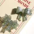 Detail of green acrylic bow accessories with glitter texture and resin finish - Green