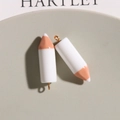 Detail shot of cute white and wood resin pencil charms for DIY jewelry on a tray - White