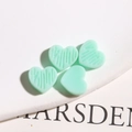 Detail van muntgroene hartvormige harsbedeltjes met getextureerde en gladde afwerking - Meer Groen