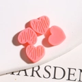 Detail van roze hars hartvormige bedeltjes met streeptextuur en gladde afwerking voor DIY - Dieproze