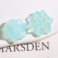 Nahaufnahme lichtblauer Harzblüten mit buntem Glitzer für die DIY-Schmuckherstellung - Klares Blau