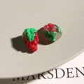 Detailed close-up of resin red grape charms with green leaves on a white ceramic plate - Grape Style