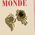 Macro detail of molten gold crescent moon pendants with black resin stone inlays - Gold Black