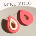Detailed view of bicolor resin teardrop hollow earrings on a grey jewelry tray - Pink & White