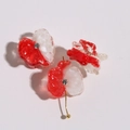 Macro shot of red and white resin flower charms with rhinestones and gold pins - Orange Red