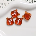 Macro detail of amber resin bear charms with cute facial prints for DIY crafts and decor - Transparent Amber