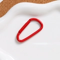 Vista macro di un moschettone a D in alluminio rosso su vassoio in ceramica bianca - Rosso