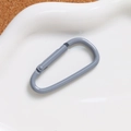 Close-up of grey matte D-ring spring buckle on white tray for DIY keychains - Gray