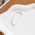 White D-ring carabiner in a ceramic cloud tray on cork background, minimalist aesthetic - White