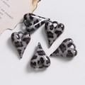 Gros plan de 5 pendentifs coeur en résine imprimé léopard pour la création de bijoux DIY - Gris