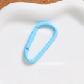Close-up of a light blue D-shaped aluminum spring hook on a white ceramic plate - Sky Blue