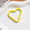 Macro shot of a bright yellow heart-shaped spring clasp on a white wavy ceramic plate - Yellow