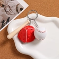 Close-up of mini wooden bat, leather glove and baseball keychain charms in a tray - Red