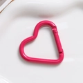 Macro shot of rose pink heart-shaped aluminum spring clasp on a white tray - Rose Red