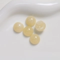 Dettaglio macro di cinque perline in resina ambrata da 12mm con trama marmorea naturale - Bianco Sporco