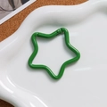 Close-up of a green star-shaped alloy spring clasp on a white plate for DIY crafts - Dark Green