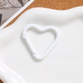 Primer plano de un mosquetón de corazón blanco en plato cerámico para llaveros DIY - Blanco