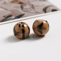 Vista macro de dos cuentas redondas de resina con estampado de leopardo para joyería DIY - Café Claro