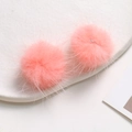 Macro detail of two soft pink mink fur pom-poms for DIY jewelry on white display tray - Peach Pink
