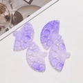 Macro detail of four purple fan-shaped acrylic pendants with floral hollow engravings - Purple