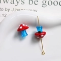 Detail of red polka dot glass mushroom bead with translucent blue stem and gold pin - Red with Blue Stem