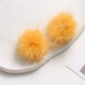 Close-up of bright yellow fluffy mink fur balls for DIY jewelry and hair accessories - Orange