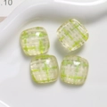 Macro view of square resin DIY charms with green and white plaid patterns on a ceramic plate - Green