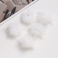 Detail shot of five soft white fluffy faux fur pompoms for DIY craft accessories - White