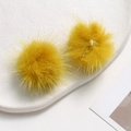 Close-up of bright yellow fluffy mink fur pompoms on a white ceramic plate for DIY crafts - Ginger Yellow