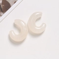 Detailed macro shot of translucent milky white C-shaped resin earrings on a clean backdrop - White