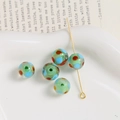 Macro view of 10mm light green glass beads with colorful polka dots on a metal pin - Green