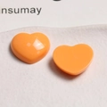 Macro shot of glossy orange acrylic heart charms for DIY jewelry and crafts - Orange