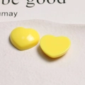 Macro shot of two glossy bright yellow heart-shaped acrylic charms for DIY crafts - Yellow