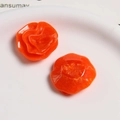 Close-up of glossy orange resin flower charms for DIY hair accessories and jewelry making - Orange