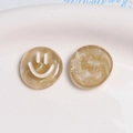 Macro detail of amber resin smiley face charms with glitter and flowing sand texture - Beige Coffee Green Glitter