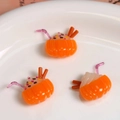 Vue macro de trois breloques citrouille en résine avec crème sur une assiette en céramique - Orange