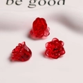 Macro detail of translucent red resin rose charms on a white ceramic plate for DIY jewelry - Burgundy