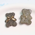 Detalle de dijes de oso en resina gris con pedrería y lazos dorados para manualidades DIY - Oso