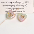 Close-up of glittery resin heart charm with gold bow and star sequins for DIY crafts - Pink and Green