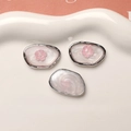 Detailed macro view of oval DIY jewelry charms with pink flower relief and pearl finish - Silver Edge White Pink Flower