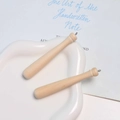 Macro detail of natural wood mini baseball bat pendants with metal eyelet on white tray - Natural Wood Color