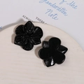 Detailed view of glossy black floral and clover resin accessories on a ceramic plate - Black