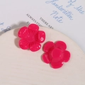 Vista macro de dos colgantes de flores de resina rosa para bisutería DIY en un plato - Rosa Roja