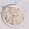 Macro shot of cream white pleated organza scrunchie on a ceramic plate detail - White