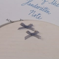 Macro detail of two light blue organza mesh ribbon bows on a white ceramic tray - Gray