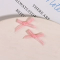 Detailed macro view of two soft pink organza fabric bows for DIY nail art and hair accessories - Pink