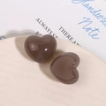 Vista macro di ciondoli a cuore in resina marrone su vassoio in ceramica per gioielli - Stile Cuore Grigio Jelly